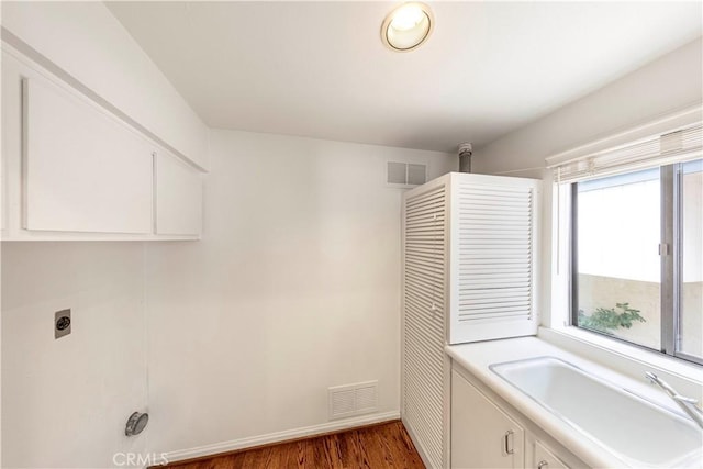 washroom featuring electric dryer hookup, dark hardwood / wood-style flooring, and cabinets