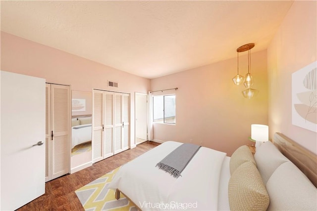 bedroom with dark hardwood / wood-style flooring, two closets, and a notable chandelier