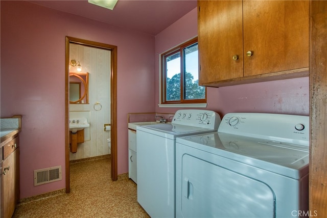 washroom with cabinets, washer and clothes dryer, and sink