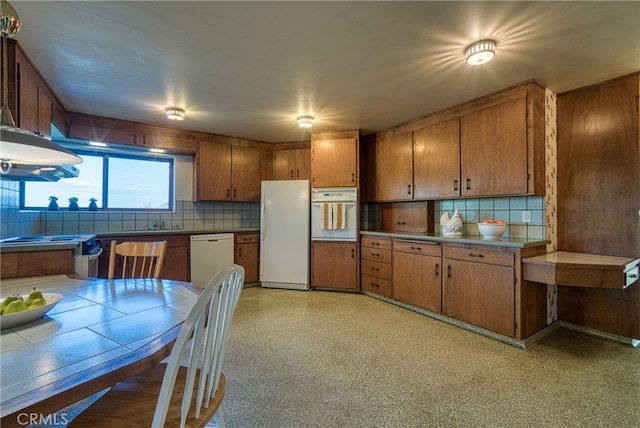 kitchen featuring white appliances, sink, and backsplash