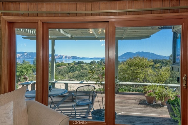 doorway to outside featuring a water and mountain view and wooden walls