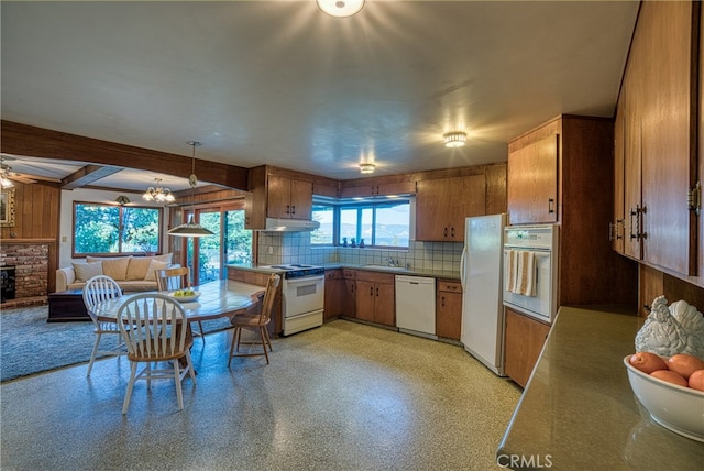 kitchen featuring hanging light fixtures, beam ceiling, sink, white appliances, and a fireplace