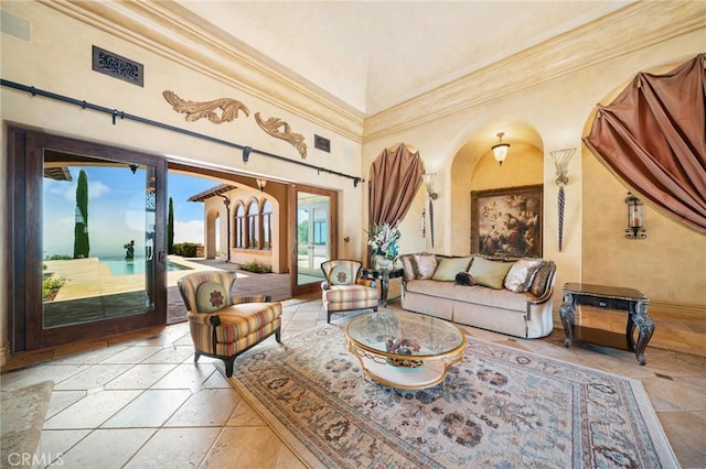 sitting room featuring a towering ceiling, crown molding, and a healthy amount of sunlight