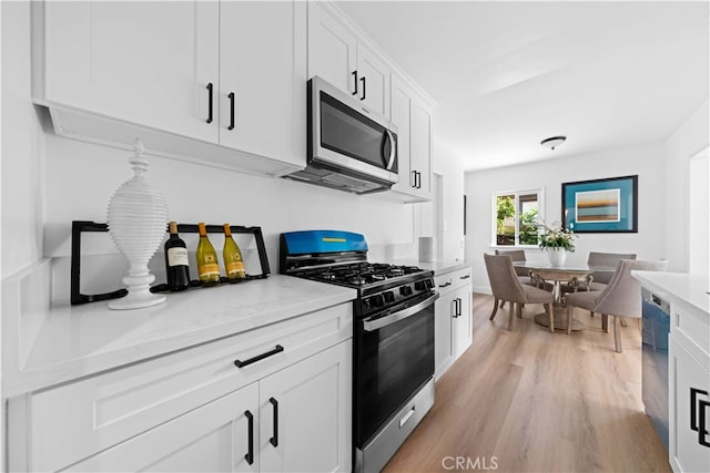 kitchen featuring light hardwood / wood-style flooring, stainless steel appliances, white cabinets, and light stone countertops