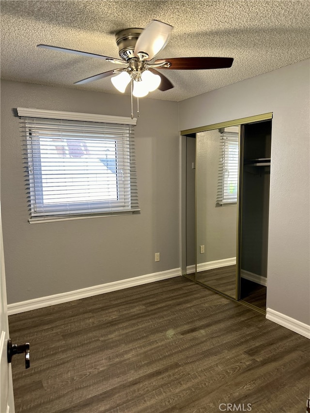 unfurnished bedroom featuring ceiling fan, dark hardwood / wood-style flooring, a textured ceiling, and a closet