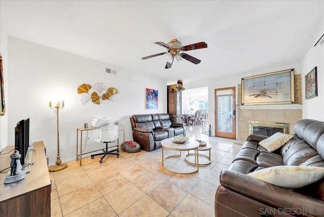 tiled living room with a tiled fireplace and ceiling fan