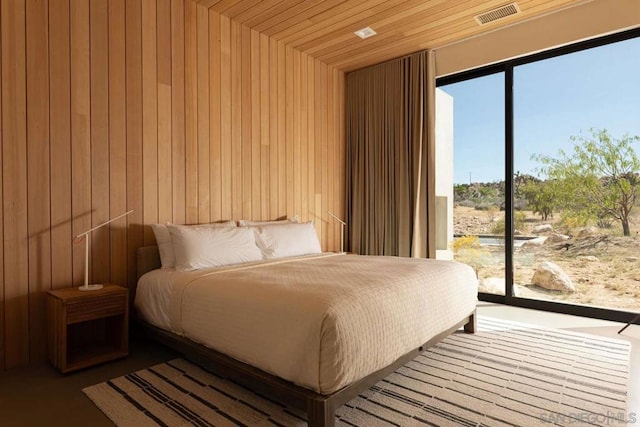 bedroom with wood ceiling, wooden walls, and access to exterior