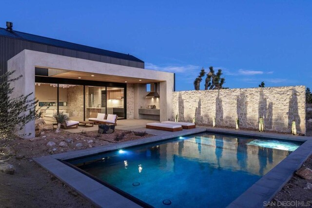 pool at dusk with a patio area