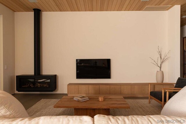 living room featuring wooden ceiling and a wood stove