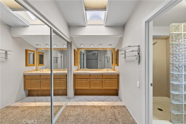 bathroom featuring a skylight, walk in shower, and vanity