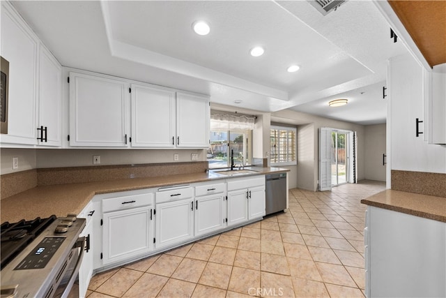 kitchen with appliances with stainless steel finishes, a tray ceiling, and white cabinetry