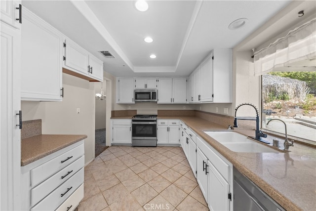 kitchen with white cabinets, a raised ceiling, light tile patterned floors, sink, and appliances with stainless steel finishes