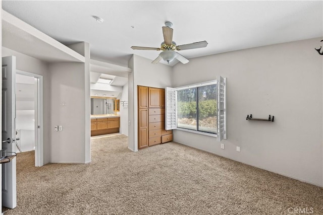 unfurnished bedroom with a ceiling fan, light colored carpet, and connected bathroom