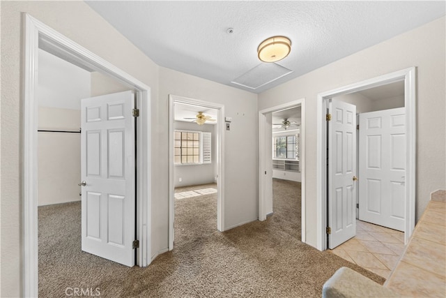 hall featuring a textured ceiling and light carpet