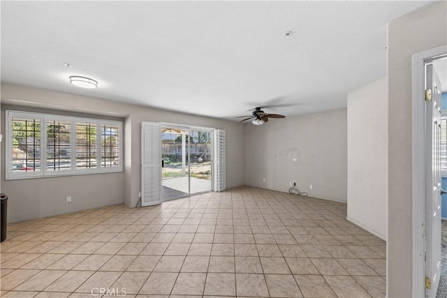 spare room with baseboards, a ceiling fan, and light tile patterned floors