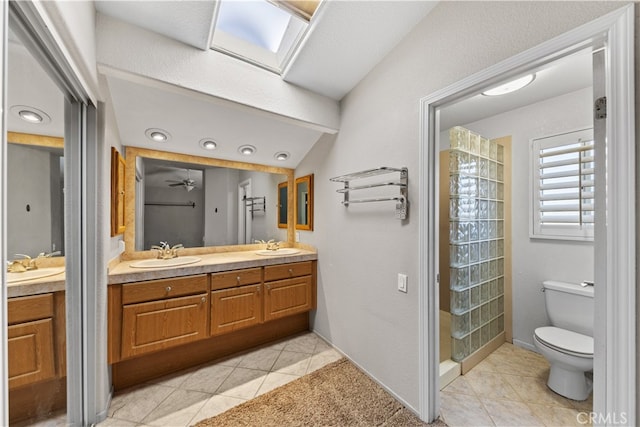 bathroom featuring tile patterned flooring, ceiling fan, lofted ceiling with skylight, toilet, and vanity