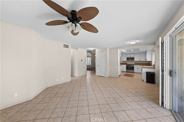 unfurnished living room featuring ceiling fan, sink, and light tile patterned floors