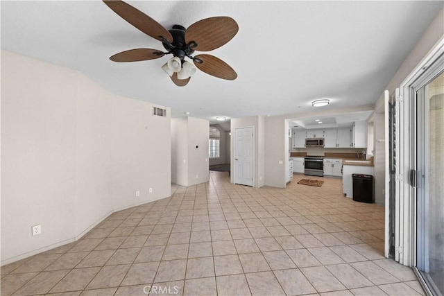 unfurnished living room with light tile patterned floors, visible vents, a sink, and ceiling fan