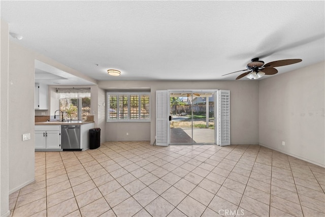 unfurnished living room featuring a textured ceiling, sink, light tile patterned floors, and ceiling fan