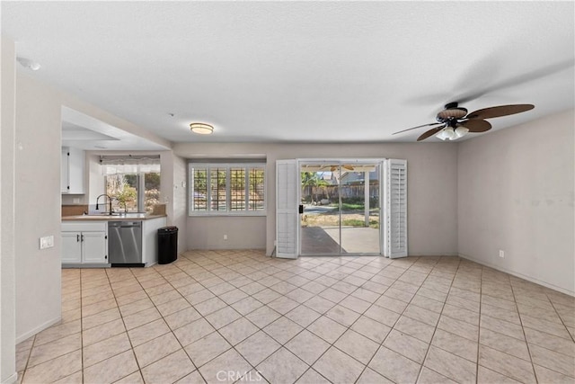 unfurnished living room featuring a ceiling fan, baseboards, a sink, and light tile patterned floors