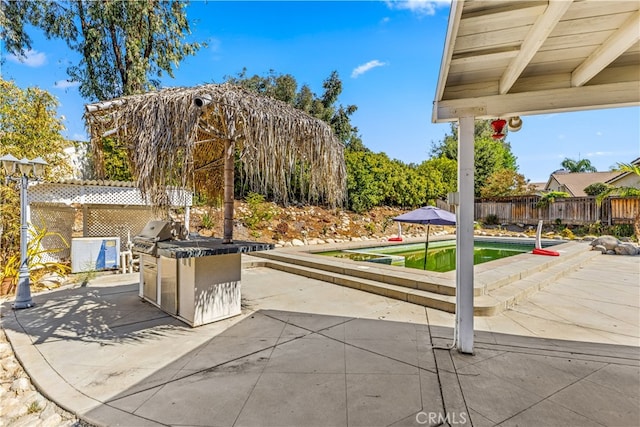 view of patio / terrace featuring a fenced in pool, an outdoor kitchen, and area for grilling