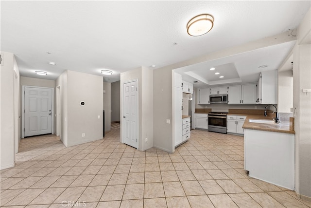 kitchen featuring light tile patterned flooring, a raised ceiling, sink, stainless steel appliances, and white cabinets