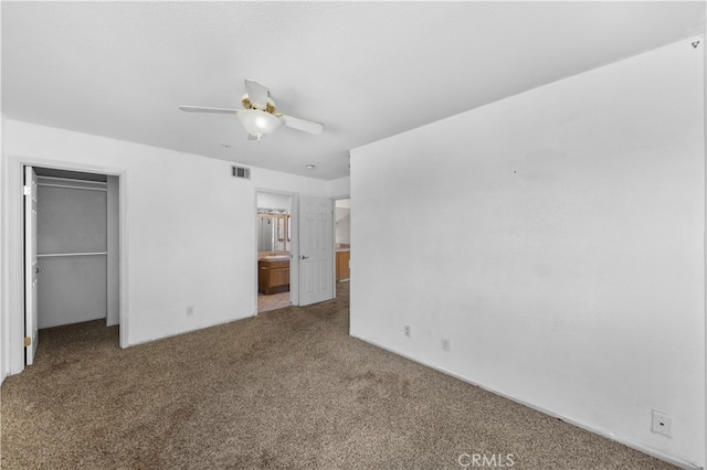 interior space with a walk in closet, carpet flooring, ensuite bathroom, ceiling fan, and a closet