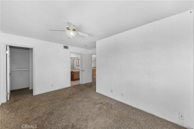 unfurnished bedroom featuring a closet, a spacious closet, carpet, ensuite bath, and visible vents