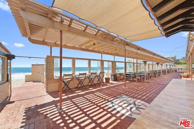 view of patio featuring a beach view, a pergola, and a water view