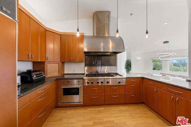 kitchen with light hardwood / wood-style flooring, pendant lighting, wall chimney range hood, and appliances with stainless steel finishes