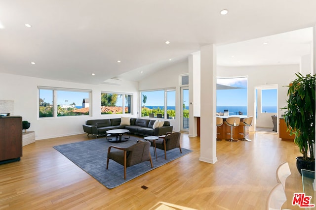 living room featuring vaulted ceiling, a water view, and light hardwood / wood-style flooring