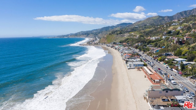 aerial view featuring a water and mountain view and a view of the beach