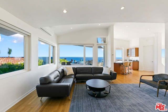 living room featuring a water view, vaulted ceiling, and light wood-type flooring