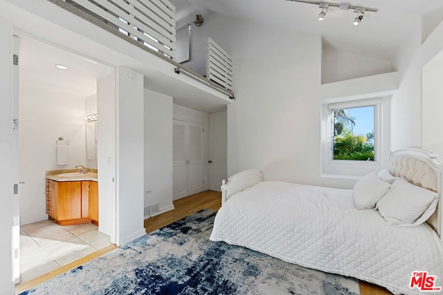 bedroom featuring light wood-type flooring, sink, high vaulted ceiling, and a closet