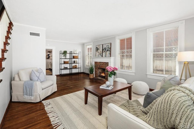 living room featuring ornamental molding, a brick fireplace, and dark hardwood / wood-style floors