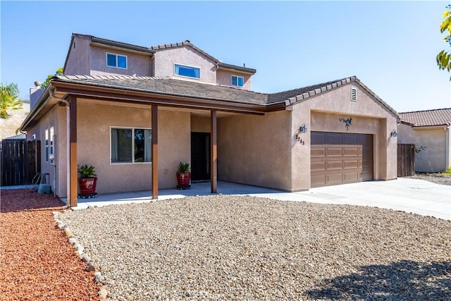 view of front of house with driveway, an attached garage, fence, and stucco siding