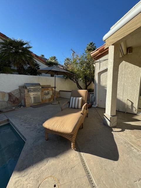 view of patio with a fenced in pool, an outdoor kitchen, and a grill