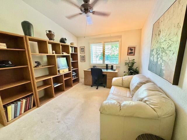 carpeted office space with lofted ceiling and ceiling fan