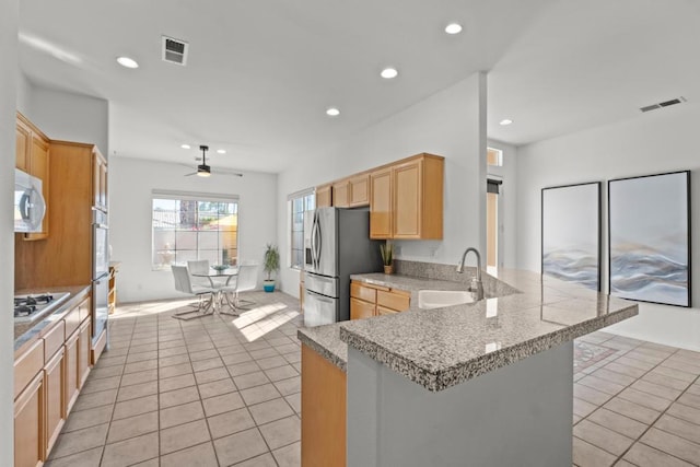 kitchen featuring kitchen peninsula, stainless steel appliances, ceiling fan, sink, and light tile patterned floors