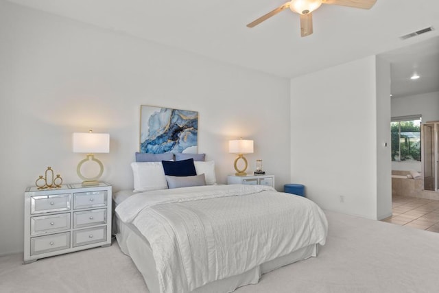 bedroom with ceiling fan, light colored carpet, and connected bathroom