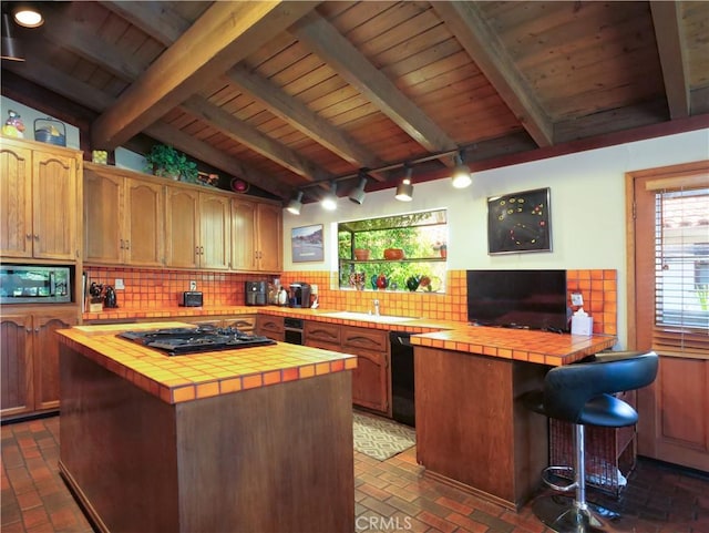 kitchen with black appliances, lofted ceiling with beams, decorative backsplash, tile counters, and a kitchen island