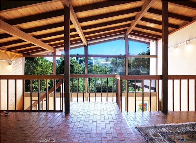 unfurnished sunroom featuring lofted ceiling with beams