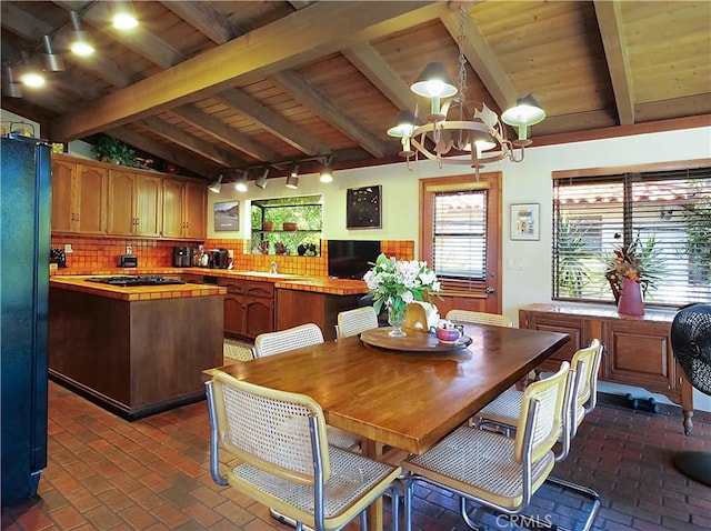 dining space with wooden ceiling, lofted ceiling with beams, rail lighting, sink, and a notable chandelier