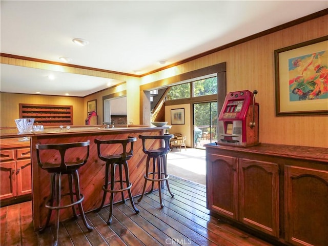 bar featuring wood walls, ornamental molding, and dark wood-type flooring