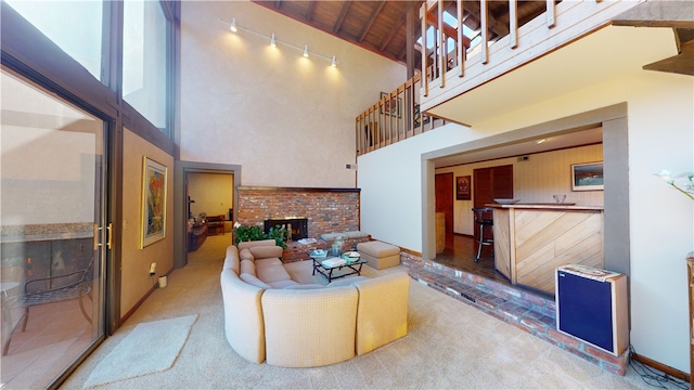 carpeted living room featuring a fireplace, a towering ceiling, and wood ceiling