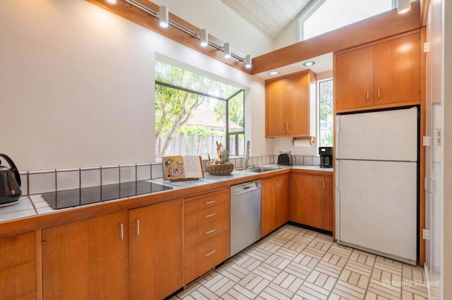 kitchen featuring tile countertops, sink, white refrigerator, black electric stovetop, and stainless steel dishwasher