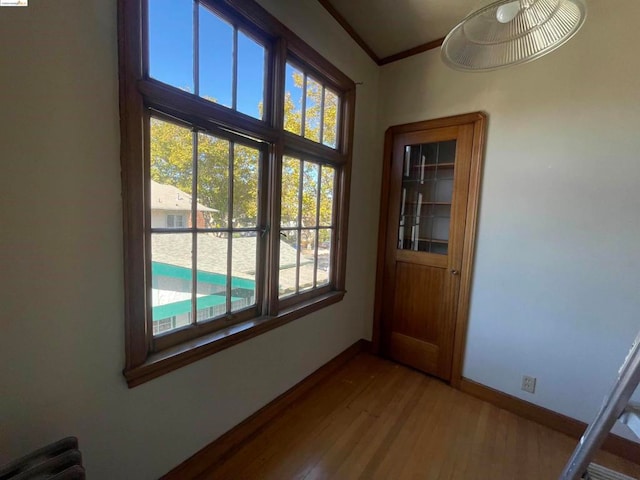 doorway to outside featuring a healthy amount of sunlight, crown molding, and wood-type flooring