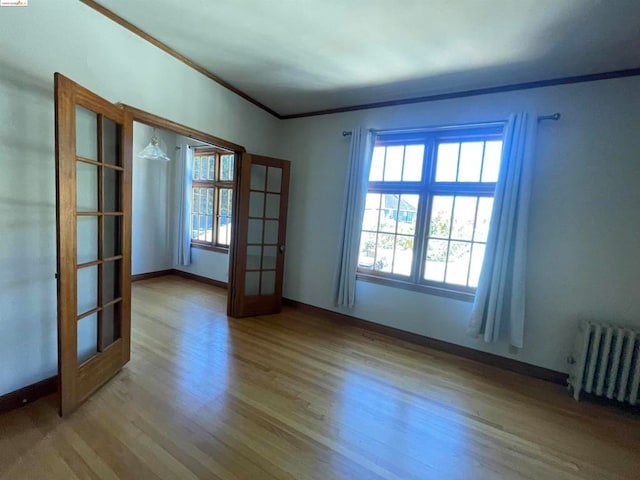 unfurnished room with french doors, radiator, ornamental molding, and light hardwood / wood-style floors