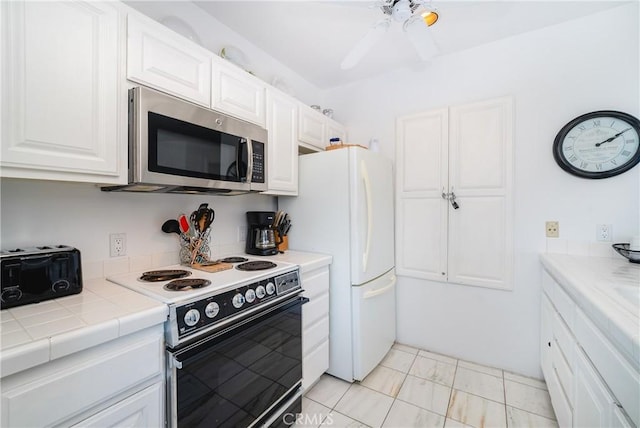 42 Camino De Flores Unit 60, Avalon, CA 90704 - kitchen featuring stainless steel microwave, black / electric stove, a ceiling fan, white cabinetry, and freestanding refrigerator