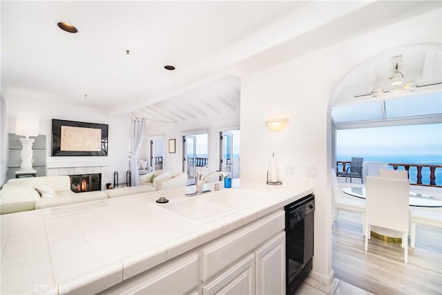 42 Camino De Flores Unit 60, Avalon, CA 90704 - kitchen with a sink, open floor plan, a glass covered fireplace, dishwasher, and tile countertops